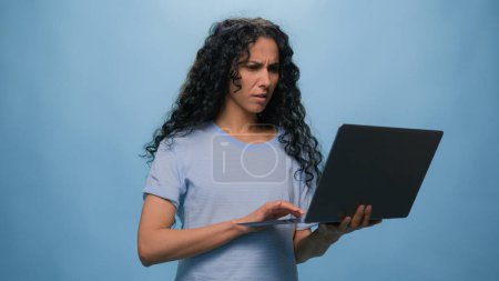 Schockiert unzufrieden verärgert traurig frustriert indische Studentin Mädchen Araberin hispanische Geschäftsfrau mit Laptop-Business-Problem Service-Fehler gebrochen Computerausfall im Studio blauen Hintergrund gestresst