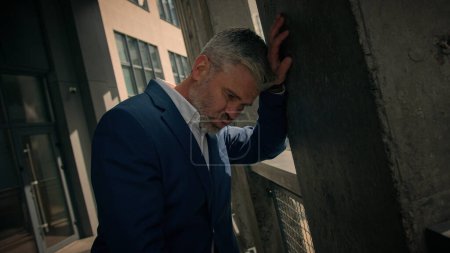 Photo for Exhausted stressed tired mature business man dizziness vertigo leaning wall of office company building 50s upset unwell fatigued Caucasian businessman take off glasses failure problem suffer in city - Royalty Free Image