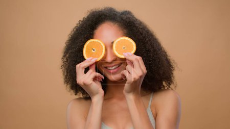 Photo for Beauty African American girl woman hold two half orange slices cover eyes dieting vegetarian body weight eco healthy vitamin skin hair care curls shampoo fruit natural organic vegan citrus cosmetic - Royalty Free Image