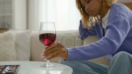 Photo for Alcohol addict alcoholic female put glass red wine on table refuse drink dependence addiction pensive relaxed sad calm African American woman girl at home couch alone think problem bad habit trouble - Royalty Free Image