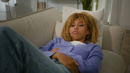 Photo for African American sad ill sadness suffering woman ethnic girl lying on couch sofa at home feeling abdominal ache belly constipation female illness menstrual pain period health problem stomach sick - Royalty Free Image