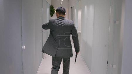 Back view adult businessman Asian ethnic man guy employer going to meeting at office hallway professional entrepreneur hurry running through corridor in business center CEO in formal suit go lateness