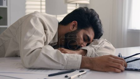 Photo for Lazy weary sleepy male manager tired exhausted Arabian Indian businessman employee working computer boring remote job man fall sleep on desktop napping in office overwork fatigue no energy sleeping - Royalty Free Image