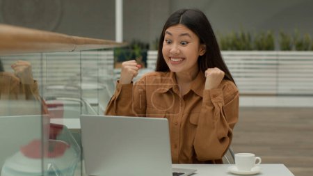 Photo for Happy shocked Asian woman businesswoman sit in cafe with laptop surprised chinese korean girl winner win job offer celebrate internet bid winning online prize scream rejoice victory success surprise - Royalty Free Image