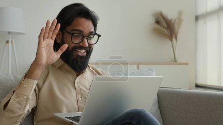 Photo for Smiling Arabian Indian muslim man talking virtual on laptop greet colleagues talk webcam video call business conference laughing friendly chatting online male businessman freelancer working from home - Royalty Free Image