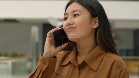 Téléchargez les photos : Asiatique femme d'affaires souriant chinois japonais fille entreprise femme employeur entrepreneur heureux coréen femme d'affaires parler téléphone mobile réponse appel parler smartphone à l'intérieur convivial bavarder au bureau - en image libre de droit