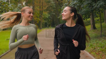 Photo for Caucasian fitness women runners two European girls young gen z sport women females running outdoors in park happy joggers fit sporty friends active jog loss weight run together morning jogging in city - Royalty Free Image