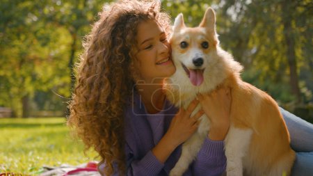 Photo for Happy woman playing kissing pedigree welsh corgi dog having fun together in park smiling joyful Caucasian girl owner play with cute puppy in summer city outdoors love animals friendship human and pet - Royalty Free Image