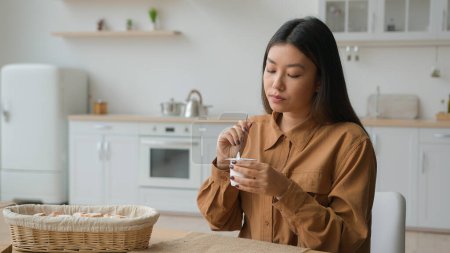 Foto de Chica china comer yogur natural saludable en la cocina doméstica asiática japonesa mujer degustación de postre desayuno por la mañana en casa coreana hambrienta mujer comer proteína yogur pérdida de peso dieta salud - Imagen libre de derechos