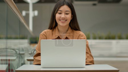 Téléchargez les photos : Femme employée de bureau asiatique femme ouverte ordinateur portable dans le café commencer à travailler en ligne avec ordinateur souriant ethnique coréen fille étudiante pigiste gestionnaire exécutif PDG employeur étudiant dans l'espace de co-travail - en image libre de droit