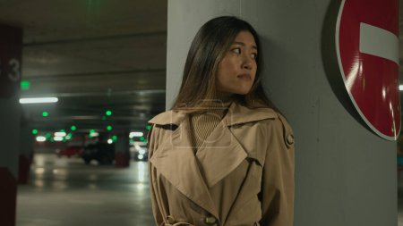Téléchargez les photos : Asiatique peur ethnique chinois coréen femme se cachant de danger poursuite menace phobie dans souterrain abri nuit sombre parking peur fille craintive se tenir seul près d'arrêter de conduire panneau de signalisation routière - en image libre de droit