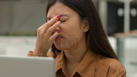 Téléchargez les photos : Surmenage asiatique femme fille de travail ordinateur portable dans le café souffrent fatigue fatigue chinoise femme d'affaires freelancer surcharge avec ordinateur de travail frotter les yeux douleur inconfort épuisement vision floue mauvaise vue - en image libre de droit