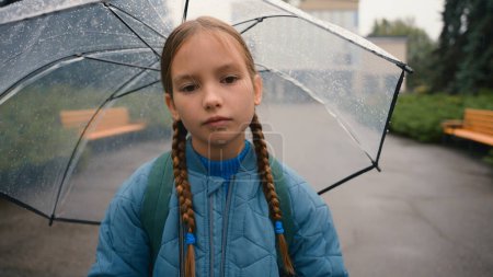 Photo for Tired little girl schoolgirl child looking at camera bored unhappy bad weather rain umbrella city park outdoors fatigue damp wet face daughter kid pupil offspring lonely sadness rainfall discomfort - Royalty Free Image