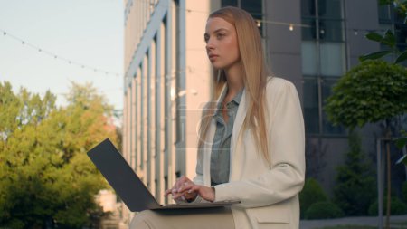 Photo for Pensive Caucasian woman businesswoman student female business lady girl developer think typing on laptop outdoors street near office work remote online thinking pondering idea journalist write article - Royalty Free Image