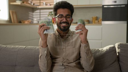 Happy rich man Arabian Indian wealthy businessman counting money cash salary finance business investment financial wage winning prize domestic finances count stack of euro banknotes at home kitchen