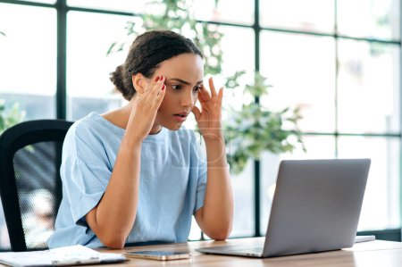 Überraschte, frustrierte Büroangestellte, die an einem Schreibtisch im Büro sitzt, enttäuscht auf den Laptop schaut, schlechte Nachrichten liest, schlechtes Arbeitsergebnis, negative Emotionen erlebt