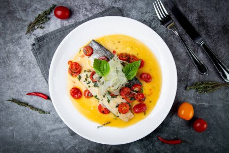 unpeeled fish with gravy, herbs, cherry tomatoes and onions