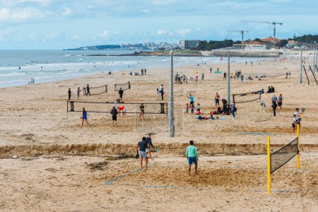 Téléchargez les photos : Lisbonne, Portugal - 17 décembre 2022 : Vue en haute perspective des personnes pratiquant le tennis de plage et le surf à la plage de Carcavelos à Lisbonne, Portugal - en image libre de droit
