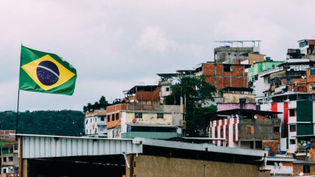 Photo for Flag of brazil on flagpole with slums in the background - Royalty Free Image