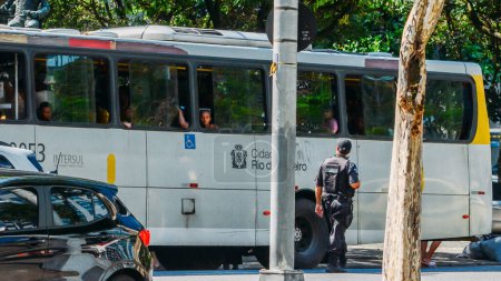Téléchargez les photos : Rio de Janeiro, Brazil - January 16, 2023: Policeman in Rio de Janeiro inspects people on a public bus in Copacabana during a routine stop - en image libre de droit