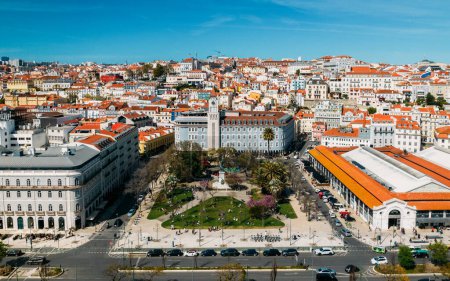 Drohnenaufnahme von Menschen, die sich im Dom Luis Garden im Baixa-Viertel von Lissabon entspannen, an einem warmen Frühlingstag mit umgebender Stadtlandschaft im Hintergrund