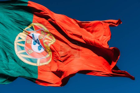 Bandera de Portugal aislada en el cielo azul ondeando en el viento.