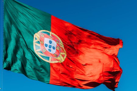 Portugal flag isolated on the blue sky waving in the wind.