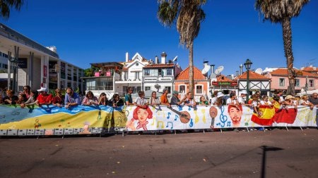 Foto de Cascais, Portugal - 3 de agosto de 2023: Personas junto a un mural de 3,5 km, el más grande del mundo, pintado por la comunidad de Cascais esperan a ver al Papa Francisco antes de su visita a Cascais, Portugal - Imagen libre de derechos