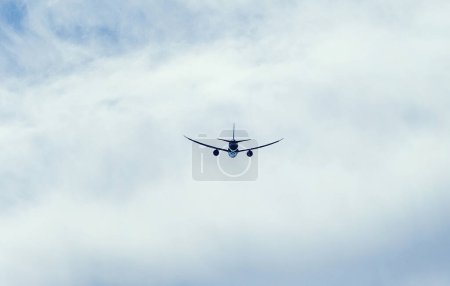 Téléchargez les photos : Un avion vole haut au-dessus du sol, coupant à travers d'épais nuages dans le ciel. Les moteurs des avions rugissent alors qu'ils traversent les nuages blancs et duveteux - en image libre de droit