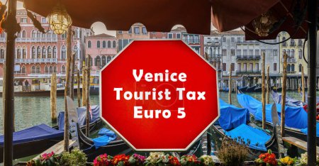 Un panneau rouge audacieux annonçant une taxe de séjour de Venise de 5 euros par jour est bien en évidence au premier plan, avec le paysage pittoresque des canaux emblématiques de Venise et des gondoles amarrées en arrière-plan.