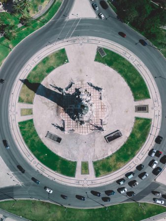 Das Bild fängt eine Luftperspektive des Marques de Pombal Kreisverkehrs in Lissabon ein und zeigt die zentrale Lage der Denkmäler. Fahrzeuge kreisen um den Kreisverkehr,
