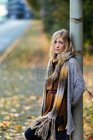 Photo for Girl woman young vamp in knitted style with blue boots and black leggings in portrait in autumnal urban location.Street art in a commercial area.She wears piercings and a knitted scarf. - Royalty Free Image