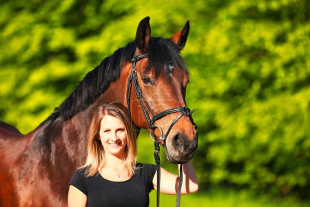Photo for Horse with young woman in portraits, in the sunshine in the wild. Isolated against a blurred green background. - Royalty Free Image