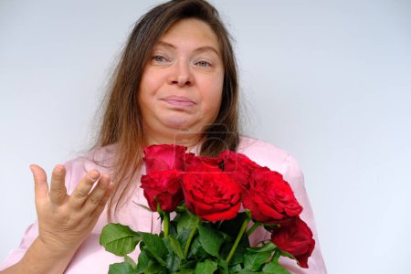 Photo for Bouquet of flowers, red roses, middle-aged woman 50 years old with bulging eyes from bewilderment and surprise, dissatisfaction with gift, flower pollen allergy, close-up emotional female portrait - Royalty Free Image