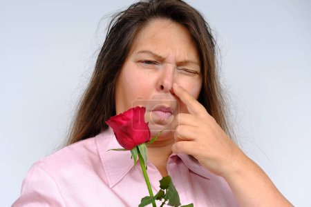 Photo for Bouquet of flowers, red roses, unhappy middle-aged woman 50 years old with bulging eyes from bewilderment and surprise, dissatisfaction with gift, flower pollen allergy, emotional female portrait - Royalty Free Image