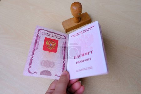 Téléchargez les photos : Passeport russe à la main étranger Passeports biométriques internationaux des citoyens de la Fédération de Russie avec couverture rouge, timbre. Arrêter le concept de migration illégale, Interdiction et suspension des visas - en image libre de droit