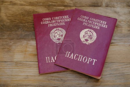 Photo for Foreign passports of citizen of the USSR, old personal document for travel in red cover on wooden table, twentieth century, bureaucracy concept, family archive , Inscription "passport" in Russian - Royalty Free Image