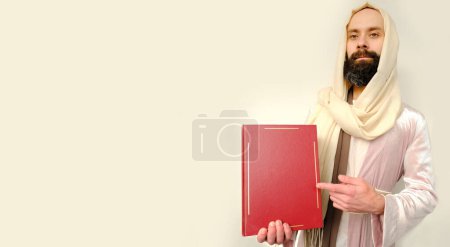Photo for Holy book of Christians, bible in red cover in hands of Jesus Christ Hand ask for follow or following offer, offering, man in image of Savior, Scriptures of Old and New Testaments, Christian religion - Royalty Free Image
