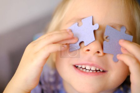 Photo for Happy cool trendy funky girl looks cheerfully into camera, happy child 4 years old creates glasses from puzzle pieces, concept of vision examination, emotional development of children - Royalty Free Image