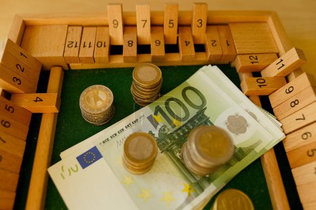 Téléchargez les photos : Close up metal euro currency coin, banknotes of european union on wooden board game Philos Shut Box, concept gambling for money, financial growth, national currency, financial devaluation, inflation - en image libre de droit