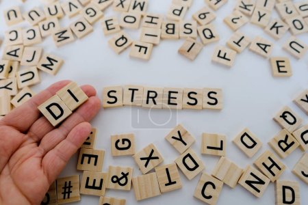 Photo for Female hand closeup holds wooden alphabet blocks on background, changes word stress to distress, concept transient negative emotional state, nervous system endurance, overload, psychological disorders - Royalty Free Image