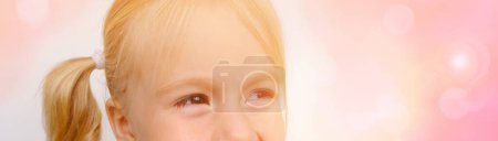 Foto de Alegre niño pequeño sonriendo, niña rubia de 3 años, parte de la cara, ojos divertidos de cerca, mirando, destello solar, infancia feliz, enfermedades oftálmicas, párpados, desarrollo emocional de los niños, panorama - Imagen libre de derechos