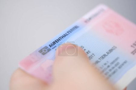 identity card, residence permit, personal document in female hand close-up with shallow depth of field, electronic communication in Europe, migration law, passport control at border, foreign travel