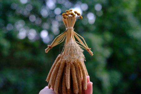 manos femeninas sostiene muñeca ritual hecha de paja, hierba en honor rica cosecha, espantapájaros para la fertilidad, juguete viejo, amuleto para las mujeres, niños, la cosecha de arte popular pagana, carácter simbólico disfrazado ritual
