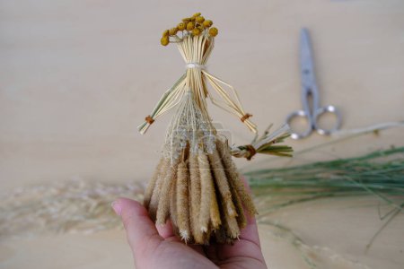 Photo for Female hands holds ritual doll made of straw, grass in honor rich harvest, scarecrow for fertility, old toy, amulet for children, pagan folk art harvesting, ritual symbolic disguised character - Royalty Free Image