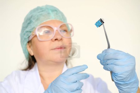 Photo for Female scientist, doctor holding microprocessor, microchip, biochip with tweezers for immunocytochemical studies organs, concept virus genotyping, experimental developments in nanotechnology medicine - Royalty Free Image