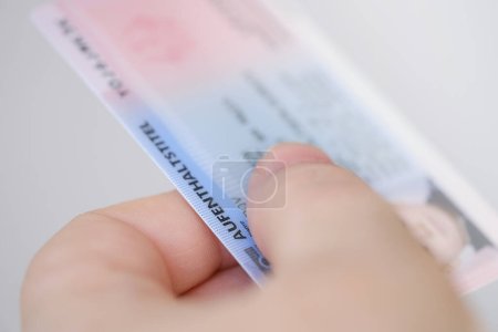 identity card, residence permit, personal document in female hand close-up with shallow depth of field, electronic communication in Europe, migration law, passport control at border, foreign travel