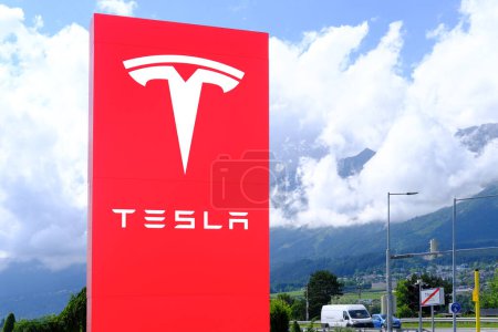 Photo for Tesla office, American company, electric car manufacturer Elon Musk, company logo on red stand, alternative energy development concept, electric vehicle production, Innsbruck, Austria - June 2022 - Royalty Free Image