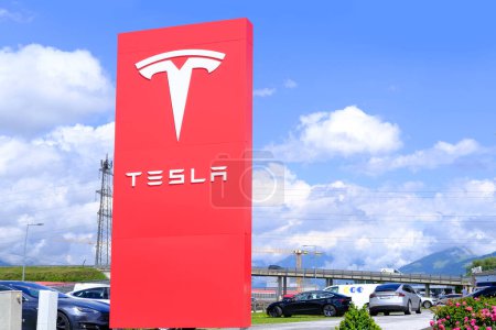 Photo for Tesla office, American company, electric car manufacturer Elon Musk, company logo on red stand, alternative energy development concept, electric vehicle production, Innsbruck, Austria - June 2022 - Royalty Free Image