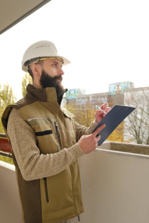 Photo for Professional male foreman in helmet during inspection in construction site, bearded man in uniform, contractor, architect on building site writing on clipboard, inspect project performance - Royalty Free Image